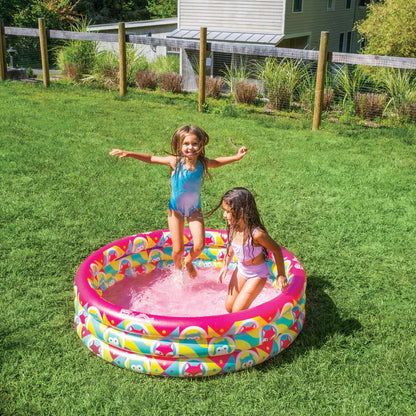 Two children playing in a colorful inflatable pool on a grassy lawn.