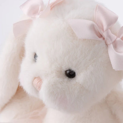 Close-up of a plush toy with a pink bow on a light background