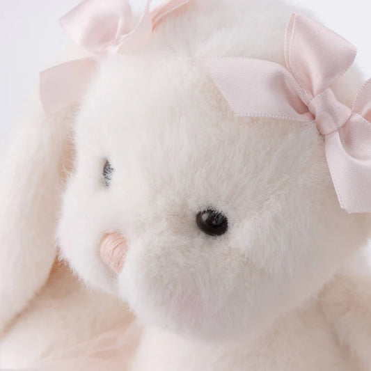Close-up of a plush toy with a pink bow on a light background