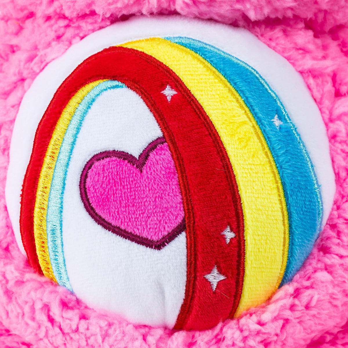 Colorful heart-shaped plush toy with rainbow design on a pink background