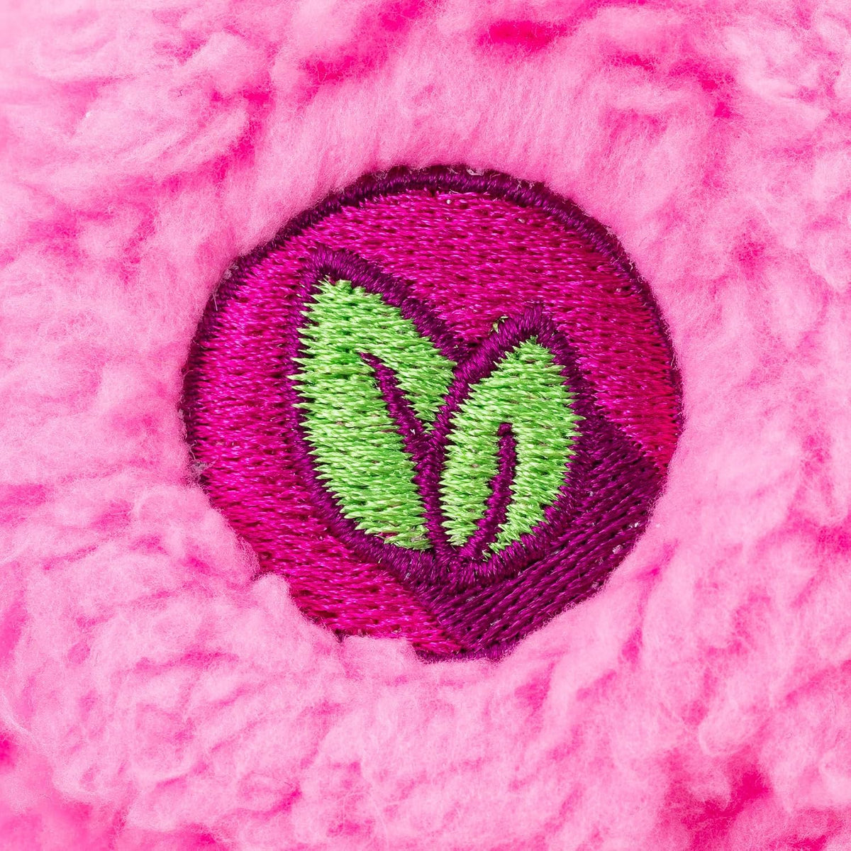 Close-up of a pink textured fabric with a green leaf emblem.