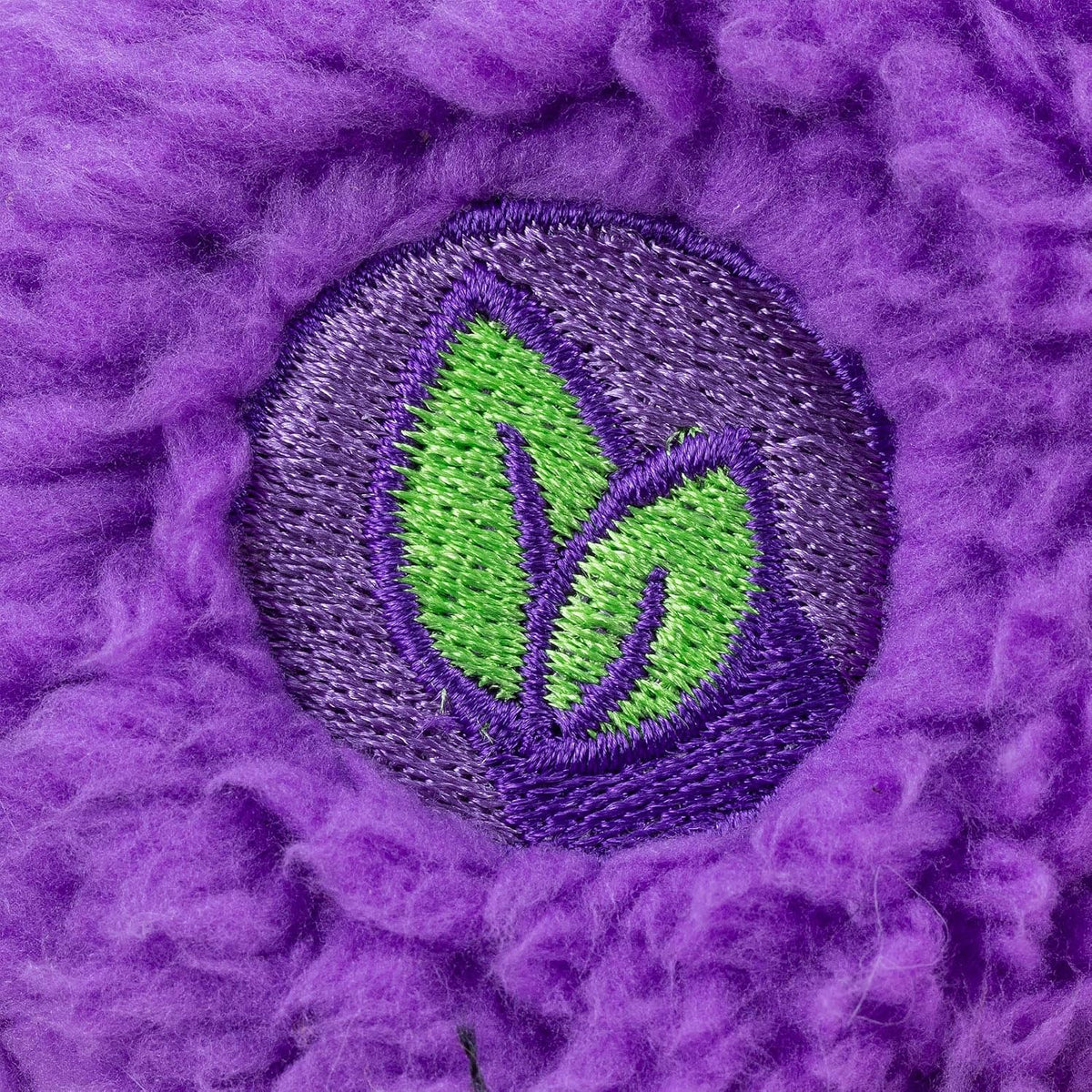 Embroidered green leaf design on a purple fabric background
