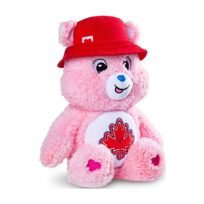 Pink teddy bear with a red maple leaf emblem and a red hat on a white background