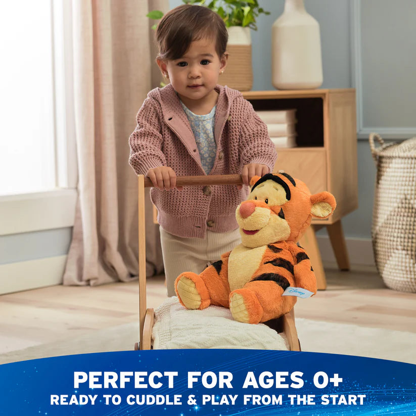 Child playing with a plush tiger toy on a small bed in a room.