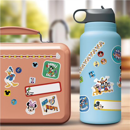 Children's lunchbox and water bottle with cartoon character stickers on a blurred outdoor background