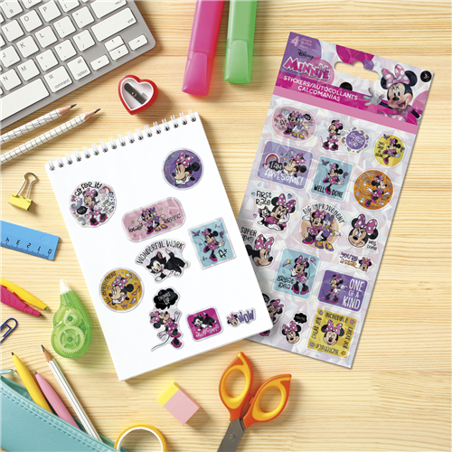 Minnie Mouse-themed stickers on a notebook with stationery items on a wooden surface