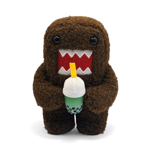 Product view of the 6.5-inch Domo plush, a brown fuzzy rectangular monster with a large open mouth holding a green boba tea cup.