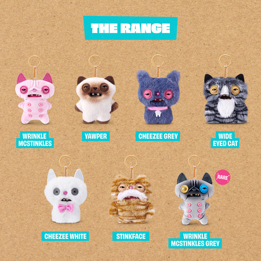 Collection of Fuggler Alley Cat keychains with labels on a brown background