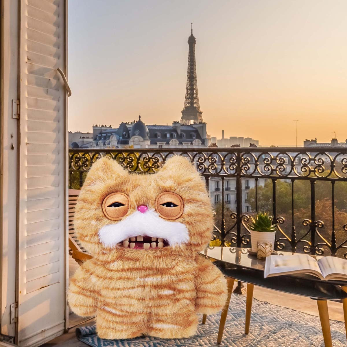 Fuggler Alley Cats Stinkface plush with a Parisian balcony and Eiffel Tower in the background