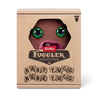 Display box of A small, roundish brown Fuggler Baby Fugg plush toy (Hedge Grog) with large green eyes, two white baby teeth showing in a pink mouth, and a spiky brown tuft of hair on top.