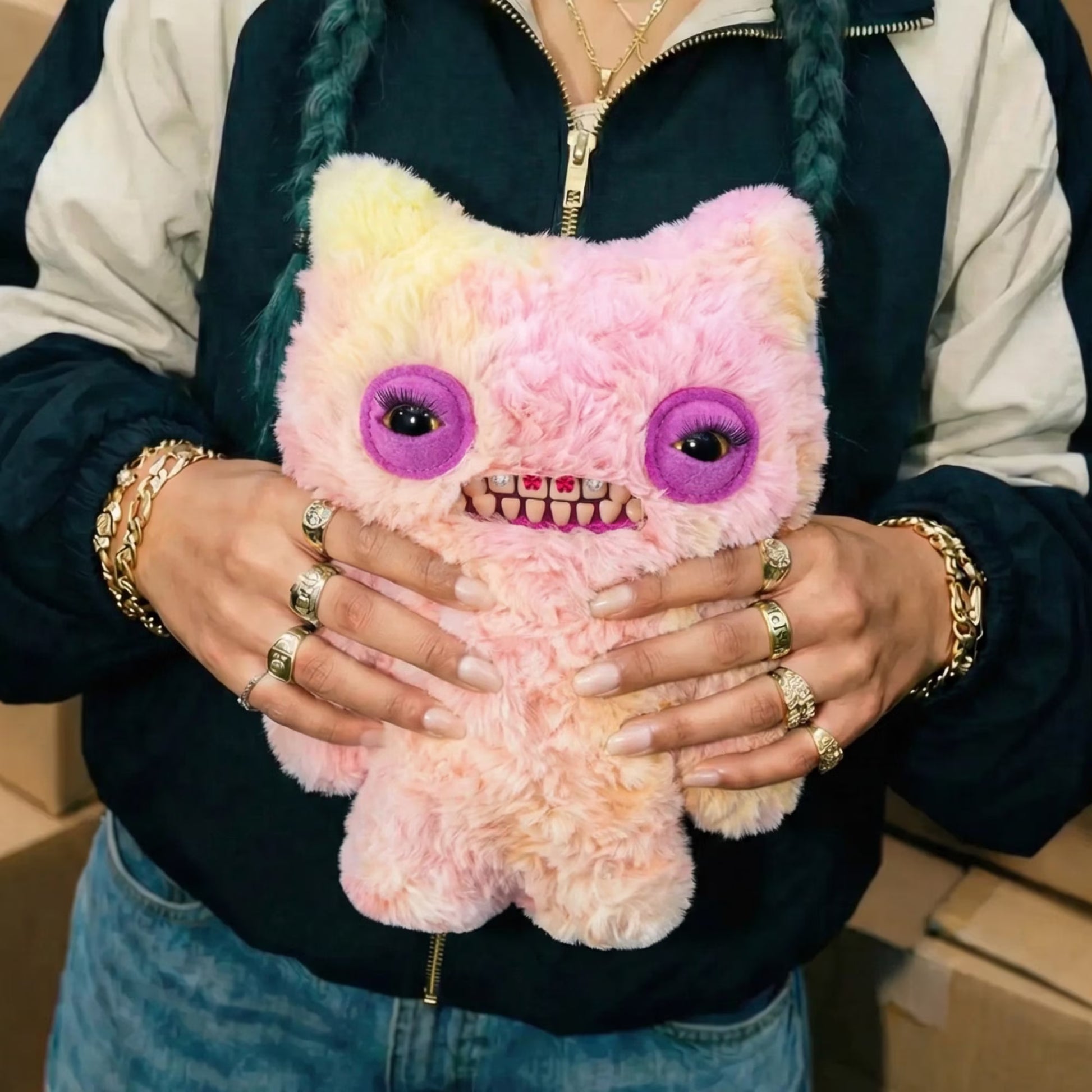Person holding a pink and yellow plush toy with purple eyes and a mouth full of teeth.