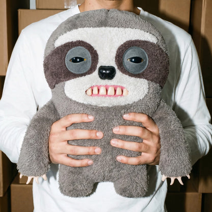Person holding a Fuggler Bigg Fugg Sickening Sloth 18-Inch Plush featuring fuzzy grey and brown fur, human-like teeth, and a sleepy, heavy-lidded expression.