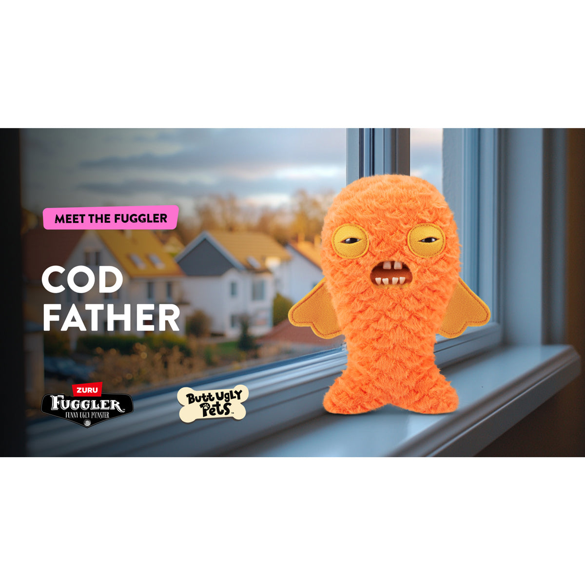 Orange plush toy with fish design on a windowsill with a view of houses outside.