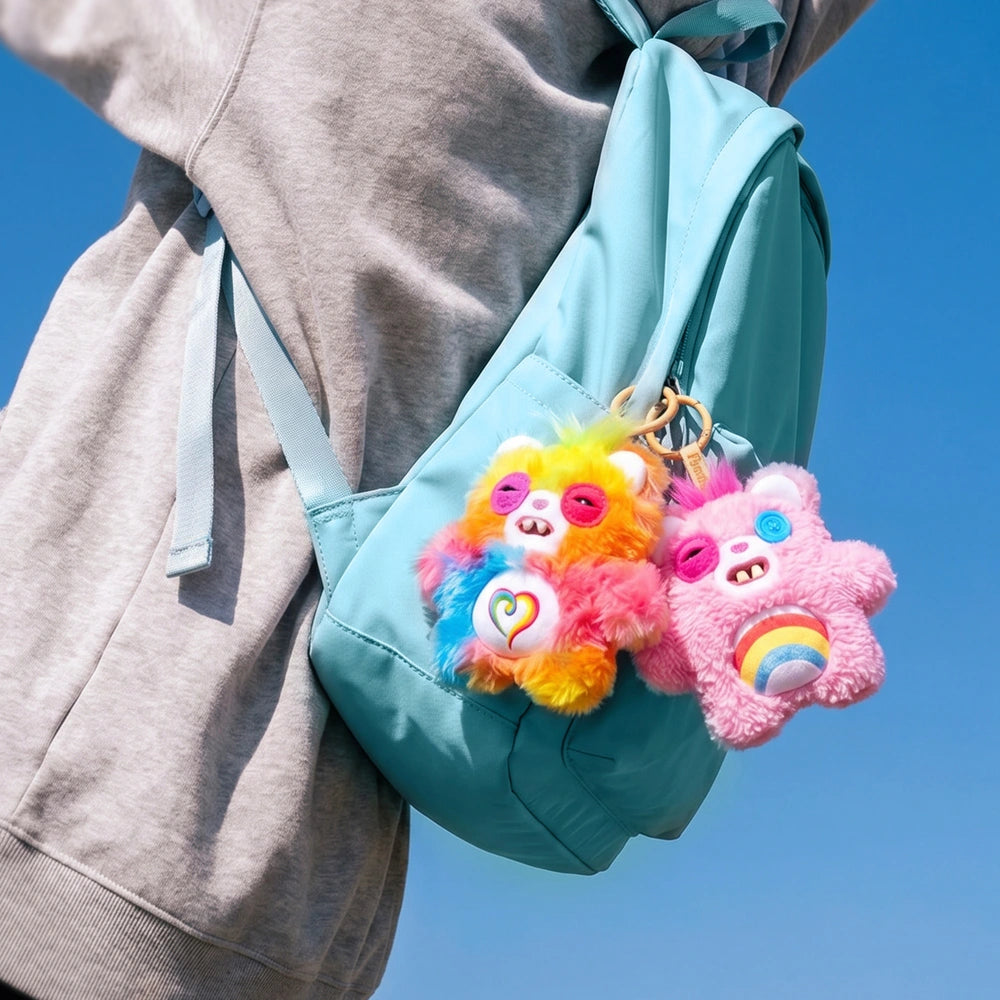 Turquoise backpack with colorful plush keychains against a clear blue sky.
