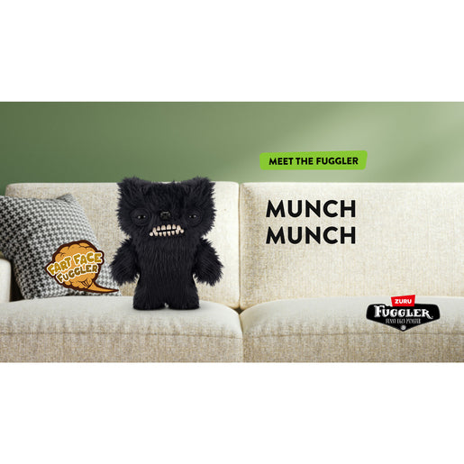 Black plush toy on a beige couch with 'Fuggler' branding. Fuggler Fart Face Munch Munch Plush by ZURU, Series 1
