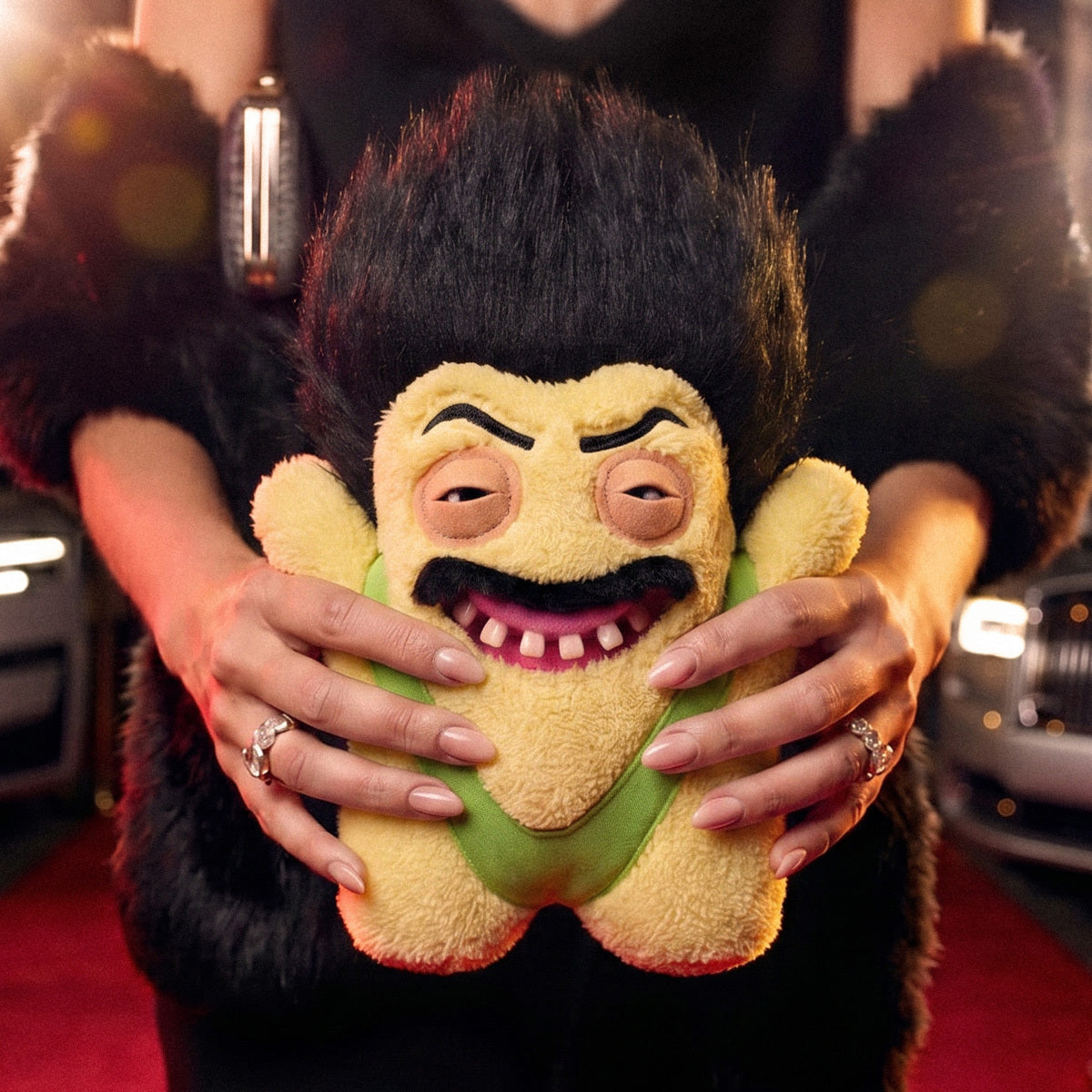 Person holding a plush toy with a distinctive hairstyle on a red carpet.