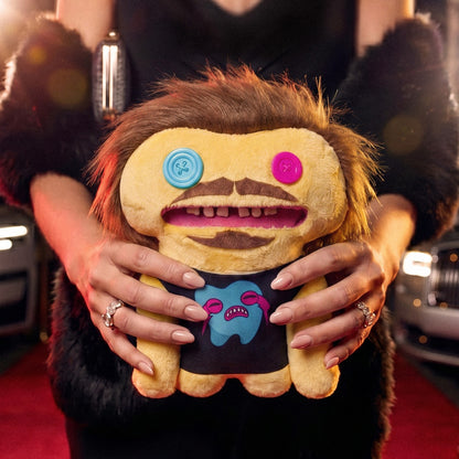 Person holding a plush toy with a unique design on a red carpet