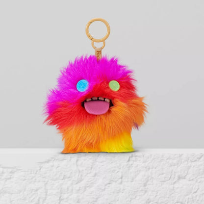 Colorful fluffy keychain with a gradient from pink to orange on a white surface.