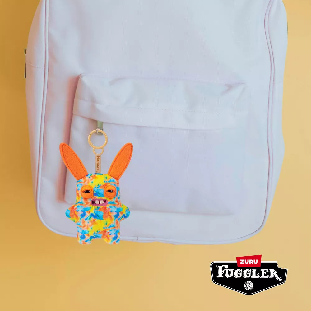 Colorful keychain with bunny design attached to a white backpack on a yellow background, featuring Zuru Fuggler branding.