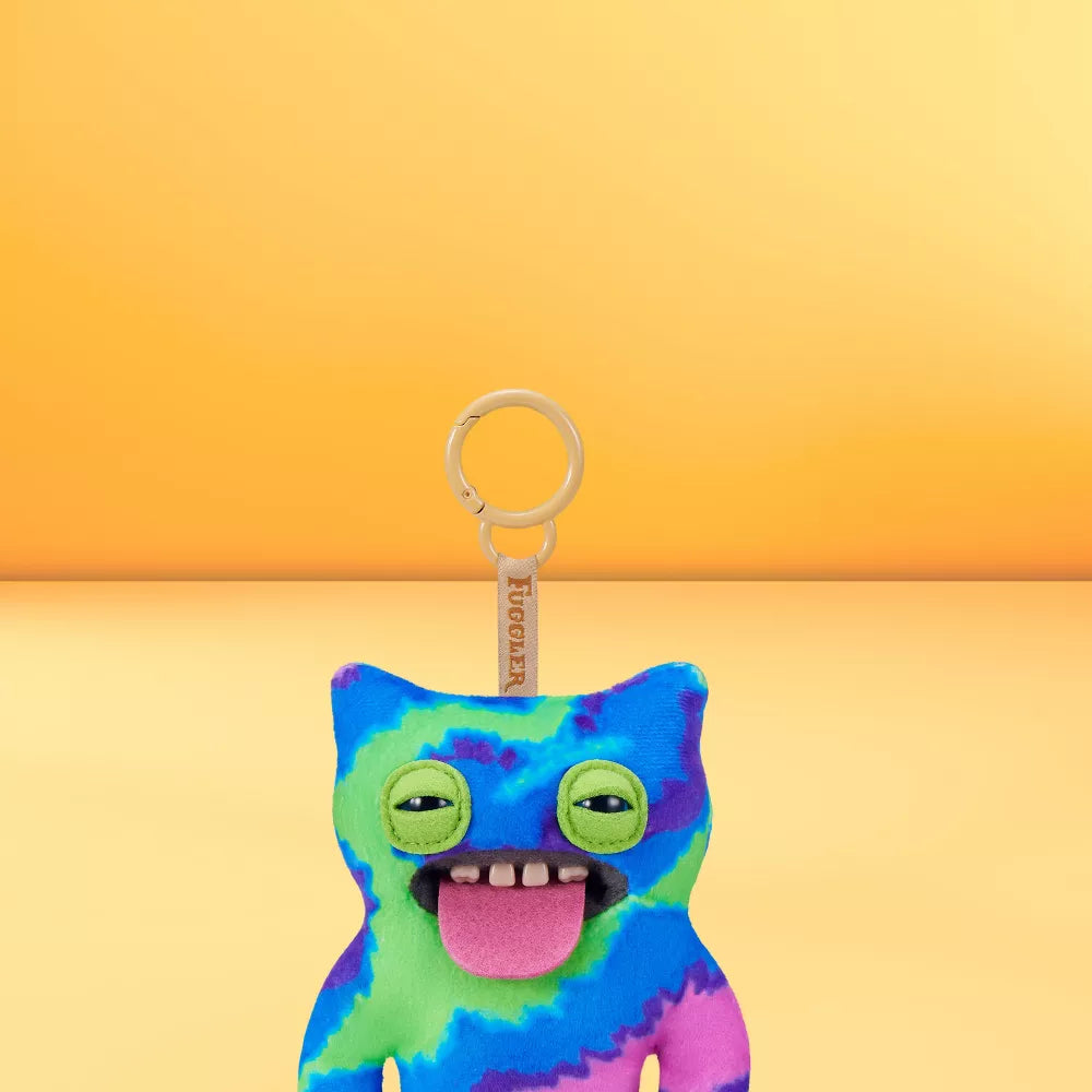 Fuggler Series 6 Sir Belch 5-inch keyring plush in Blue Tie-Dye variation, featuring vibrant green, blue, and purple fleece, green slitted eyes, and a sticking out tongue on a yellow background.