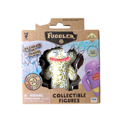 Fuggler Series 3 Gold Edition Grin Grin Leopard vinyl figure with white skin, gold spots, and a wide toothy grin in a 24 Carats of Chaos window box.