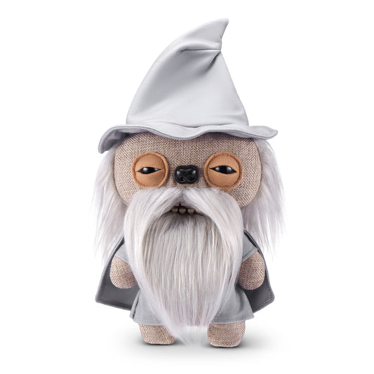 A product shot of the Fuggler x Lord of the Rings Gandalf 9-Inch plush toy, featuring a grey wizard hat, a long white fuzzy beard, and a mouth with human-like teeth.