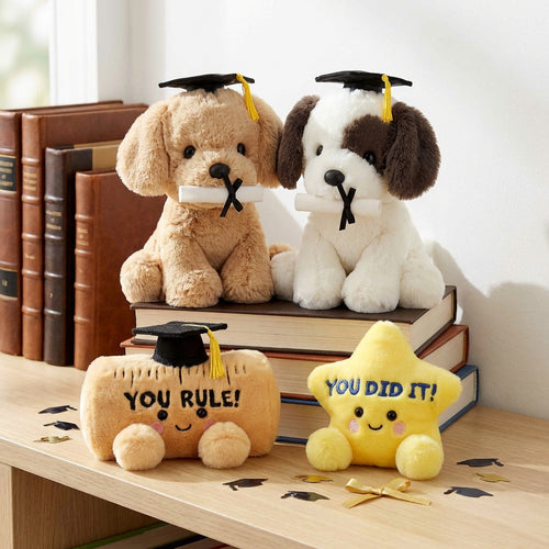 Two plush dogs with graduation caps and a small plush pumpkin with 'YOU RULE!' text, sitting on books.