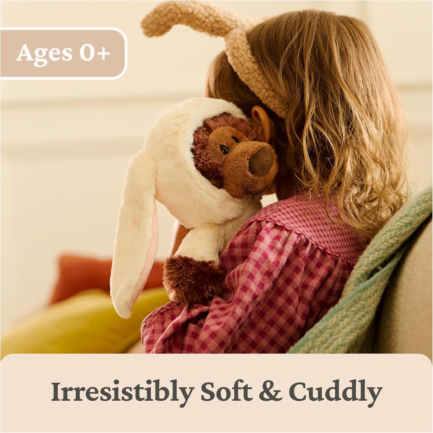 Child holding a plush toy with bunny ears, sitting on a couch.