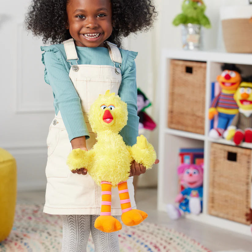 Child holding a yellow plush toy in a room with shelves and toys.