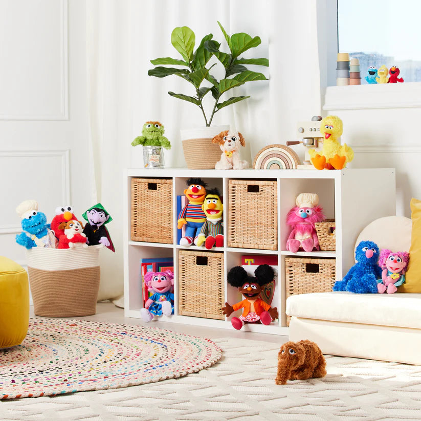 Children's toys and plushies on a white shelf with wicker baskets in a bright room.