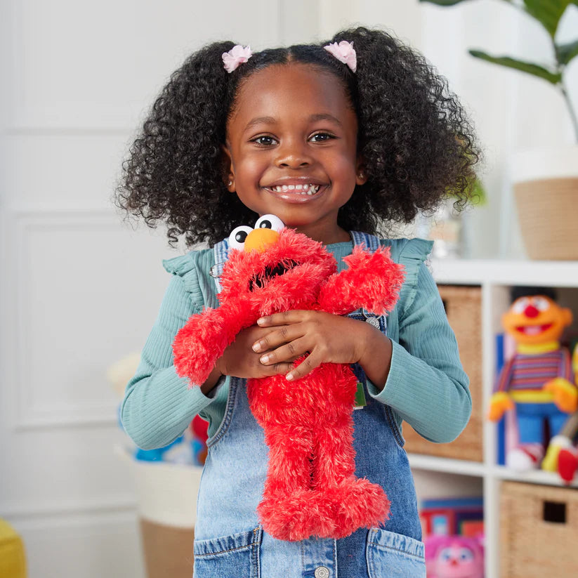 Child holding a red plush toy with a smiling expression in a room with toys in the background