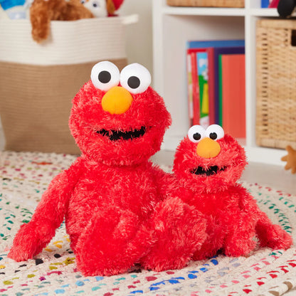 Two red plush toys with large eyes and yellow noses on a colorful blanket.