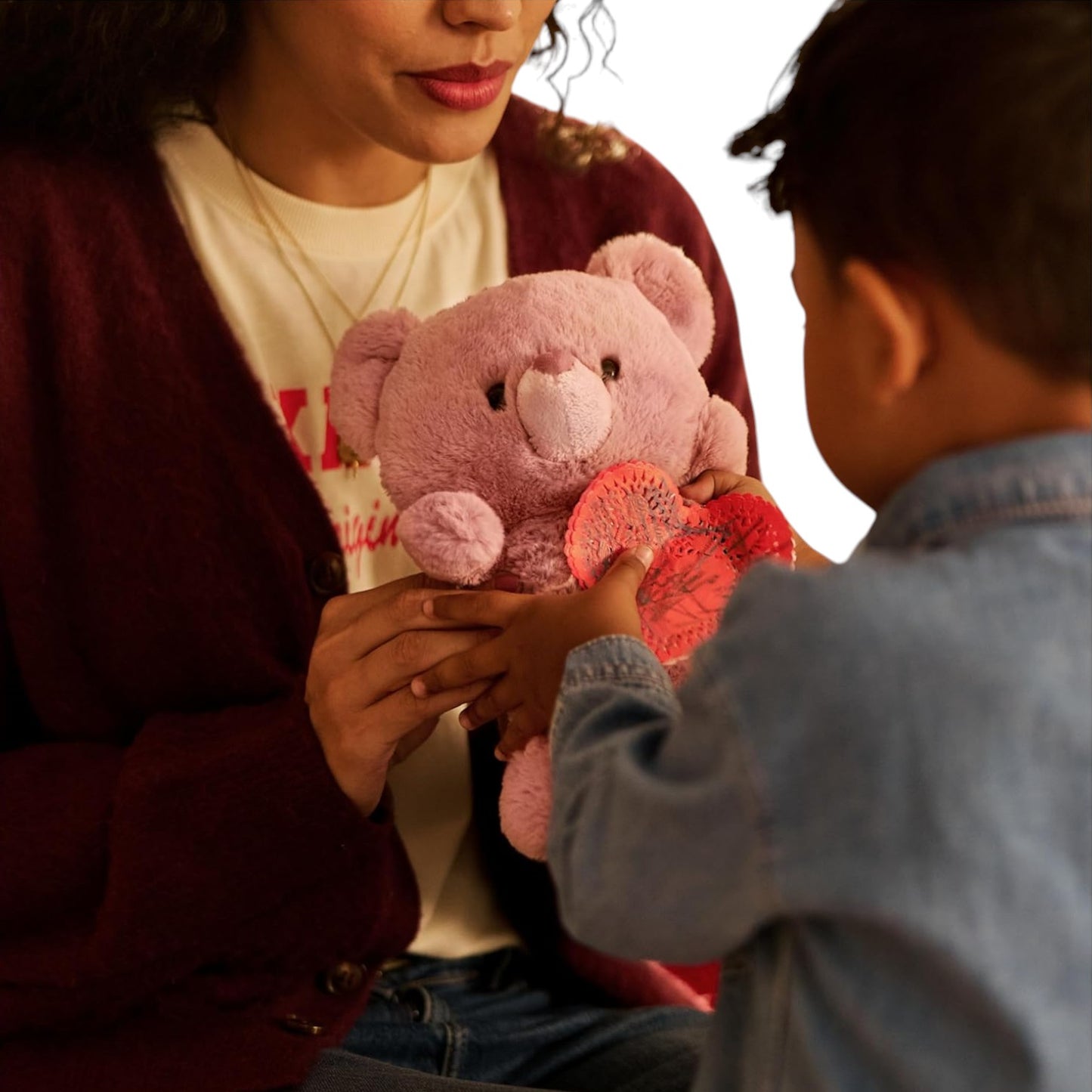Person holding a pink teddy bear with a child on a white background