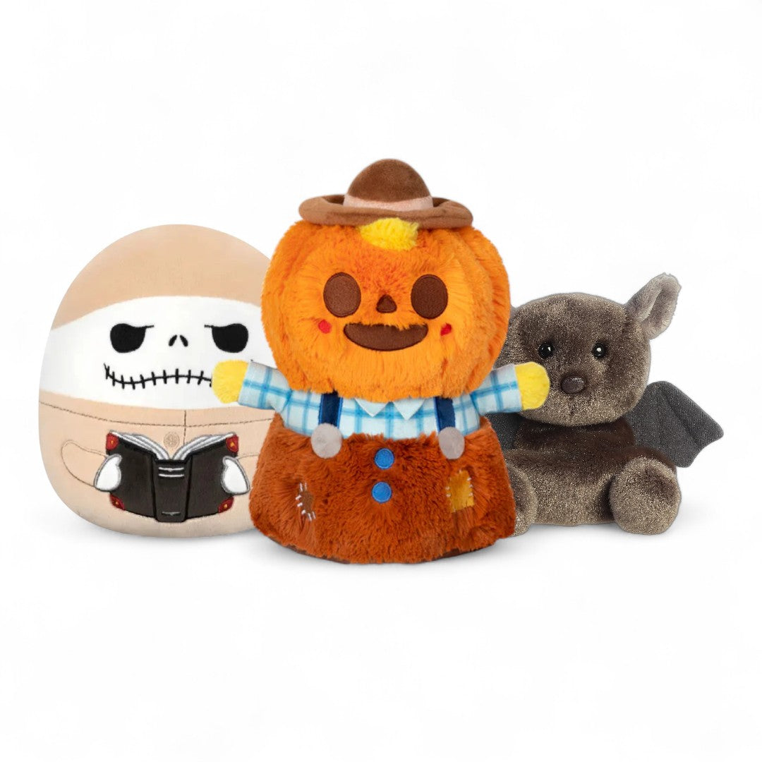 Three plush toys: a ghost, a pumpkin with a hat, and a bat, on a white background.