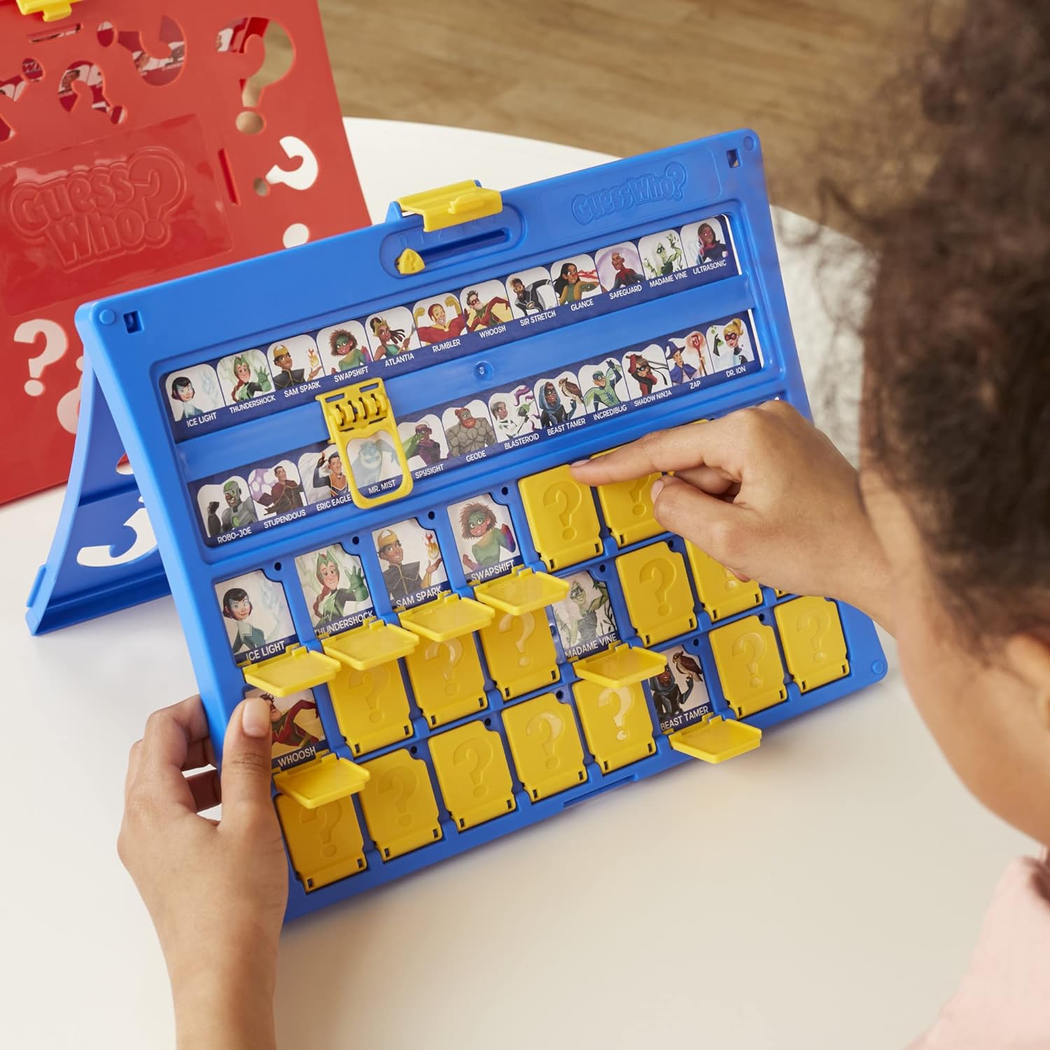 Child playing with a board game featuring character cards on a white surface.