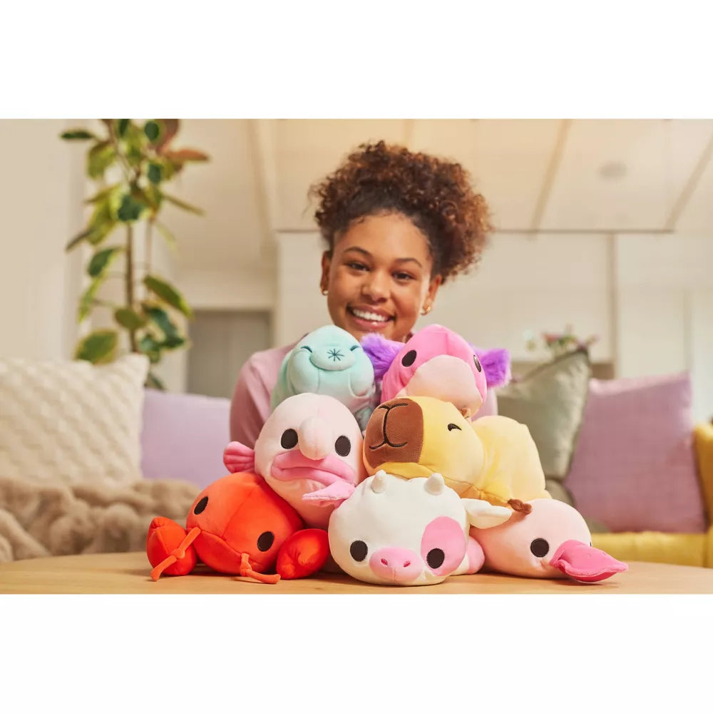 Person with a stack of Small Hug-A-Lumps Series 2 weighted plush toy by ZURU on a table