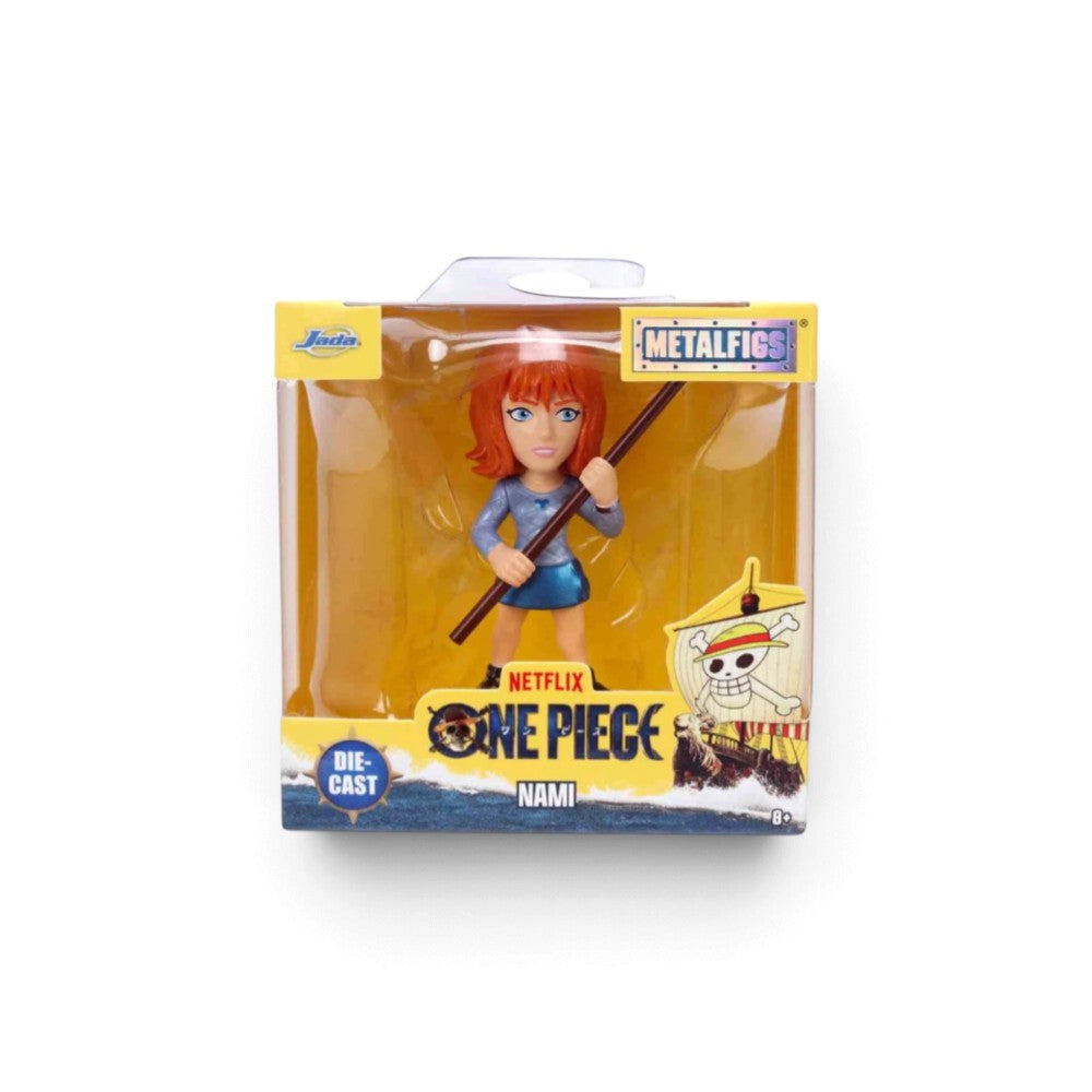 A packaged One Piece Metalfigs Nami die-cast action figure on a white background. The figure is shown through a clear plastic window in its original yellow and blue retail box, holding a long pole.