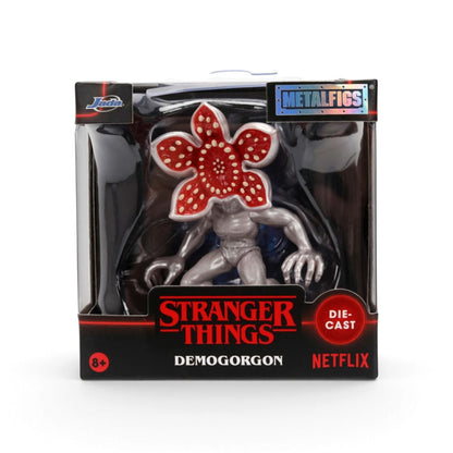 Stranger Things Demogorgon die-cast metal figure in its original window box packaging, featuring a metallic silver body and a red flower-like head with white dots, with branding for Metalfigs, Stranger Things, and Netflix.