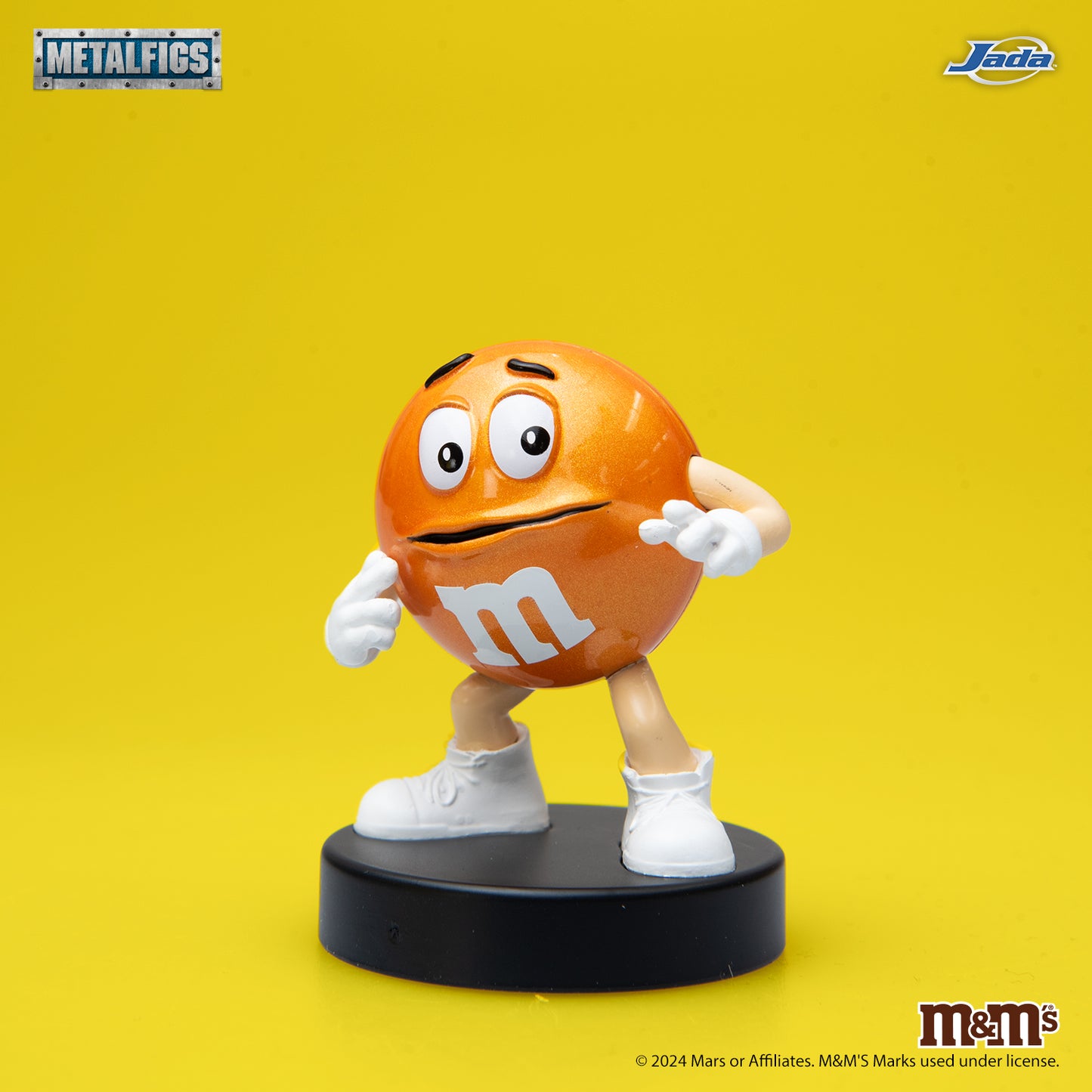 Jada Toys M&M's Orange Character 2.5-inch die-cast metal figure standing with a nervous expression and hands on his face on a black pedestal.