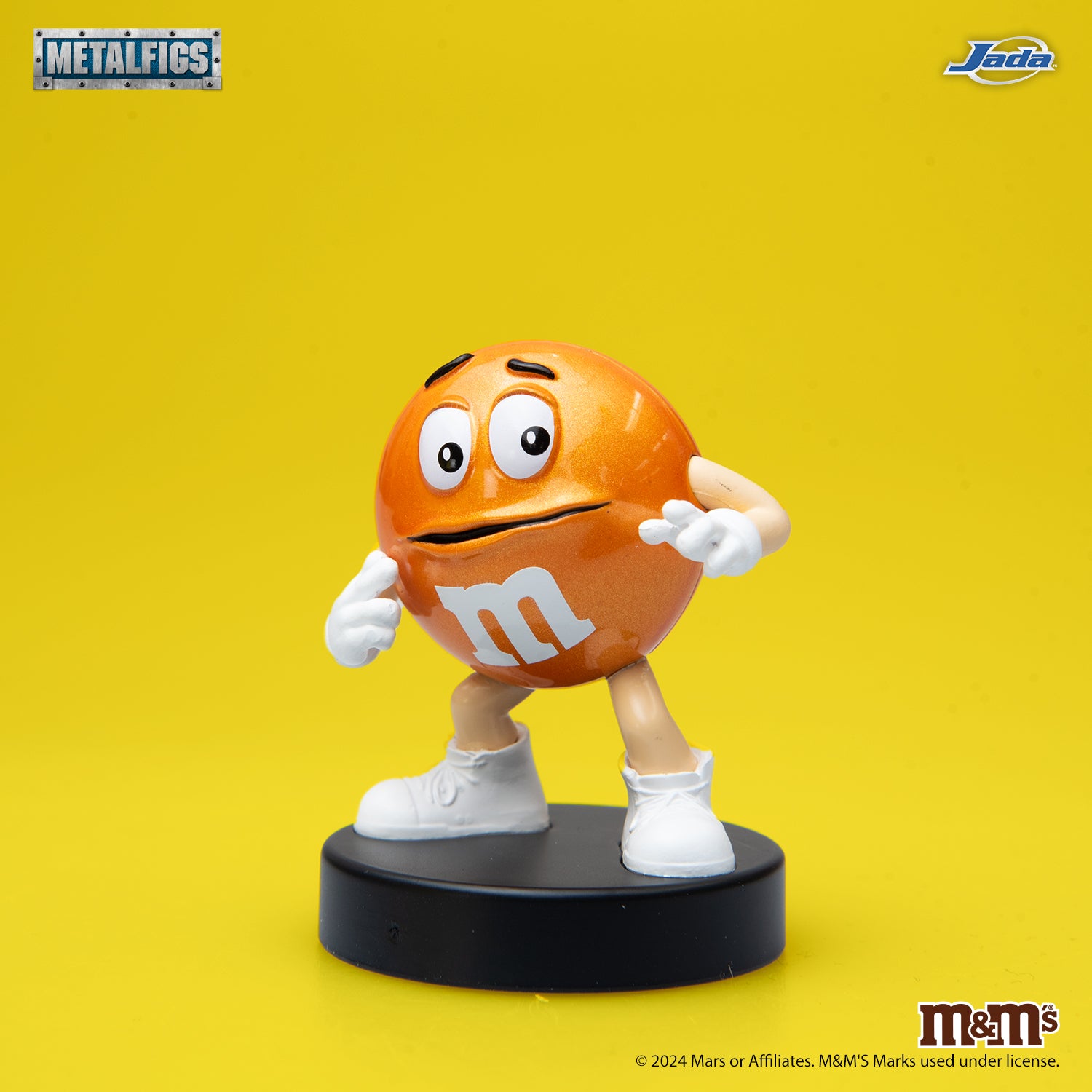 Jada Toys M&M's Orange Character 2.5-inch die-cast metal figure standing with a nervous expression and hands on his face on a black pedestal.