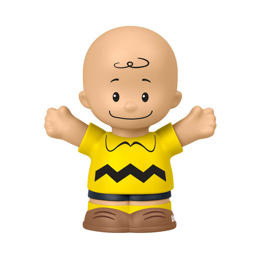 A small Charlie Brown toy figure with a bald head, black curly hair detail, and arms outstretched, wearing a yellow shirt with a black zigzag line and brown shorts, isolated on a white background.