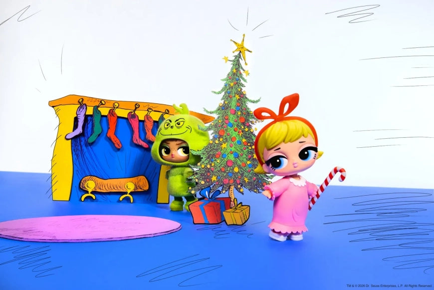 A stylized holiday scene with two cartoon doll-like characters beside a decorated Christmas tree, stockings, and gifts on a blue floor against a white background.