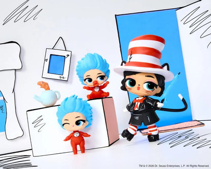 Three small stylized collectible figures posed in a hand-drawn, paper-craft-like scene. One figure wears a large red-and-white striped hat and black-and-white outfit with a blue bow, while two smaller figures with bright blue hair wear red outfits.