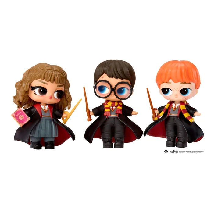 Three chibi-style Harry Potter character figures standing side by side on a plain white background. The figures wear black robes with red and yellow accents, hold wand-like sticks, and one holds a pink book.