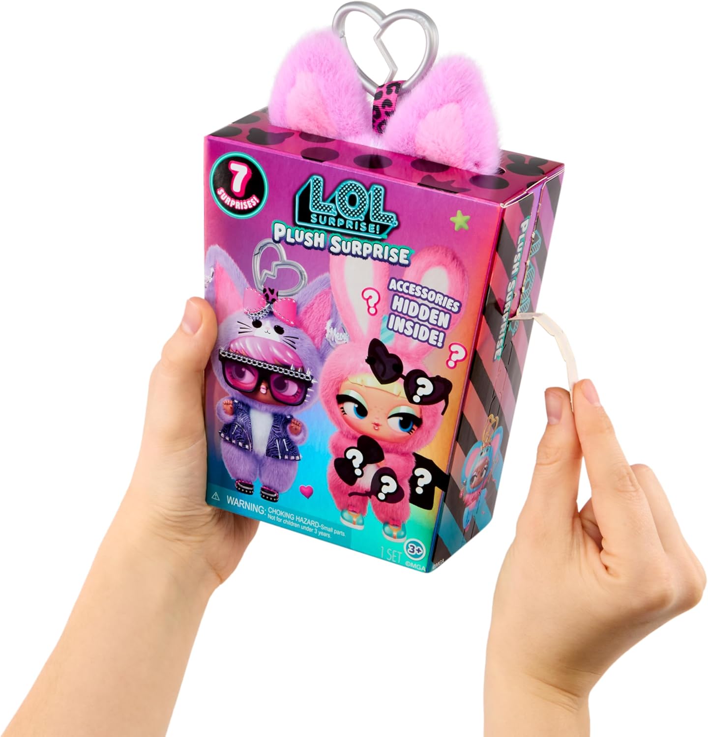 A person holds a LOL Surprise Plush Surprise toy box against a white background. The pink box features cartoon doll artwork, a heart-shaped metal clasp, fluffy pink ears, and a white pull tab on the side.