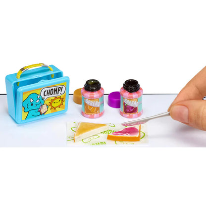 Miniature food items and a small blue suitcase with 'CHOMP!' branding on a white background.