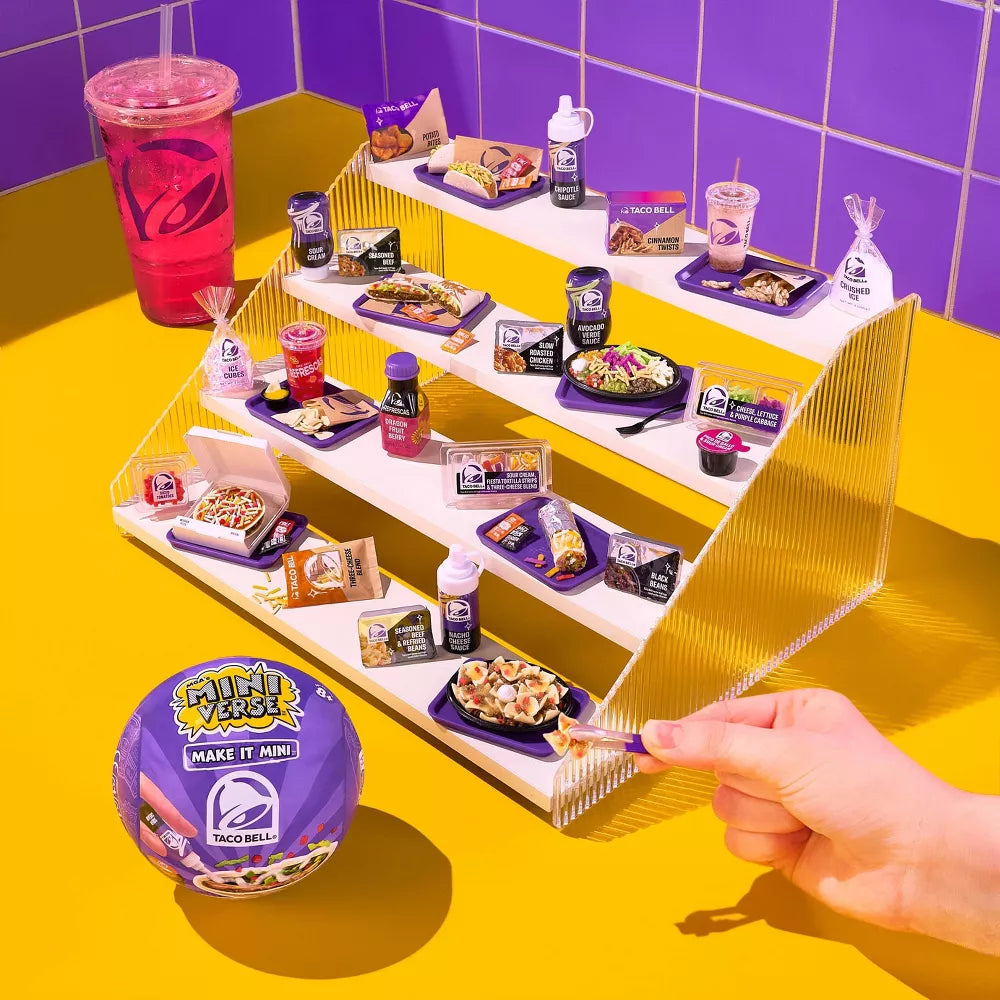 Mini Taco Bell food items on a tiered display with a hand reaching for a piece of food.