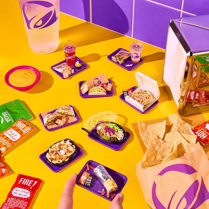 Colorful display of Taco Bell food items and packaging on a yellow table.