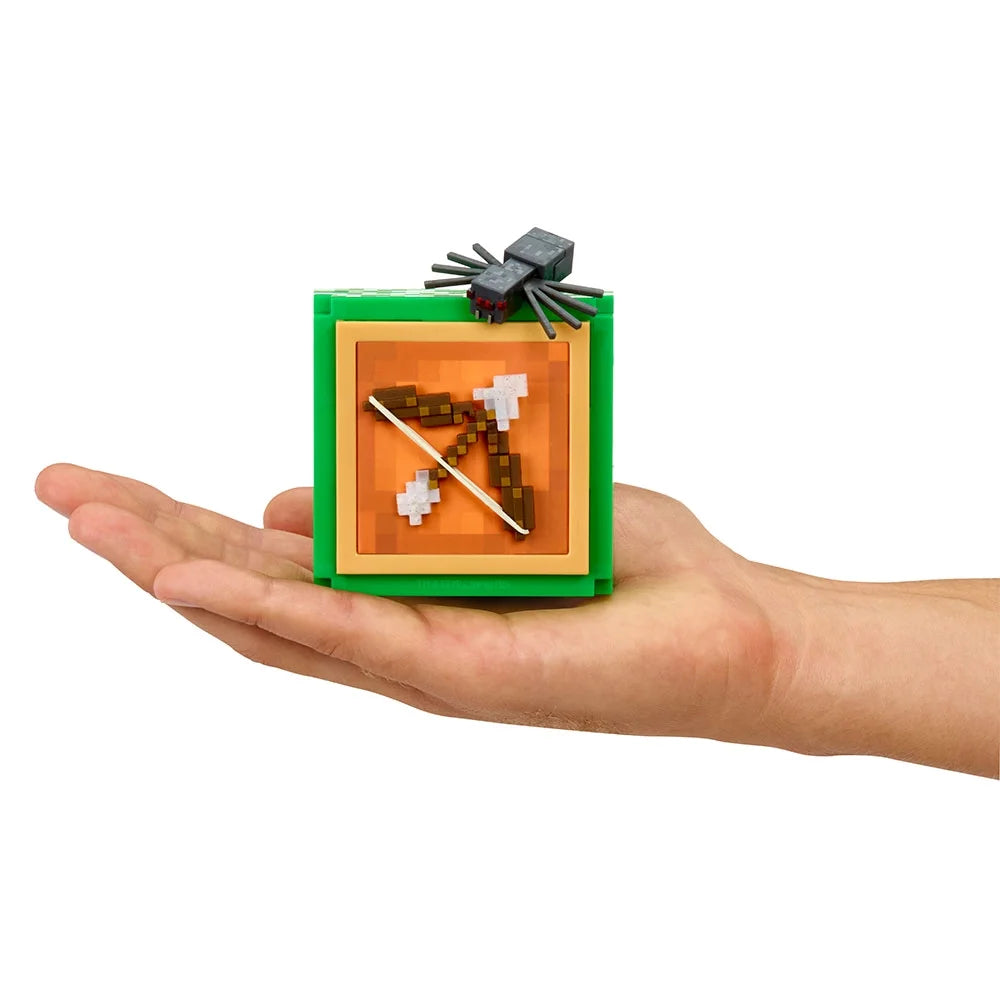 Hand holding a completed miniature Minecraft Bow and Arrow display block topped with a tiny Spider mob figure.
