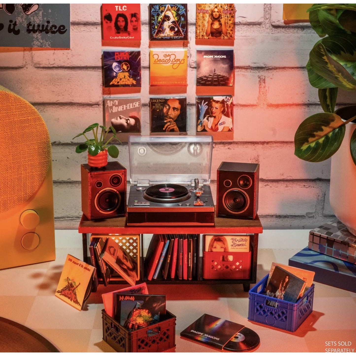 A retro-style record store display set featuring a turntable with speakers, CD shelves, record crates, a speaker, and a brick wall backdrop with album art.